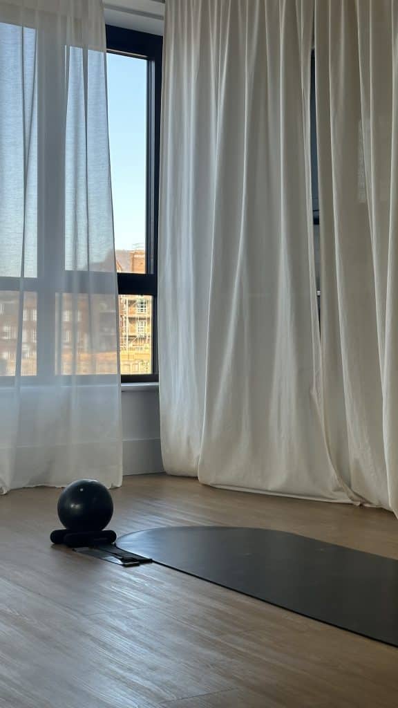 fitness studio with window, white curtains, exercise mat and exercise ball