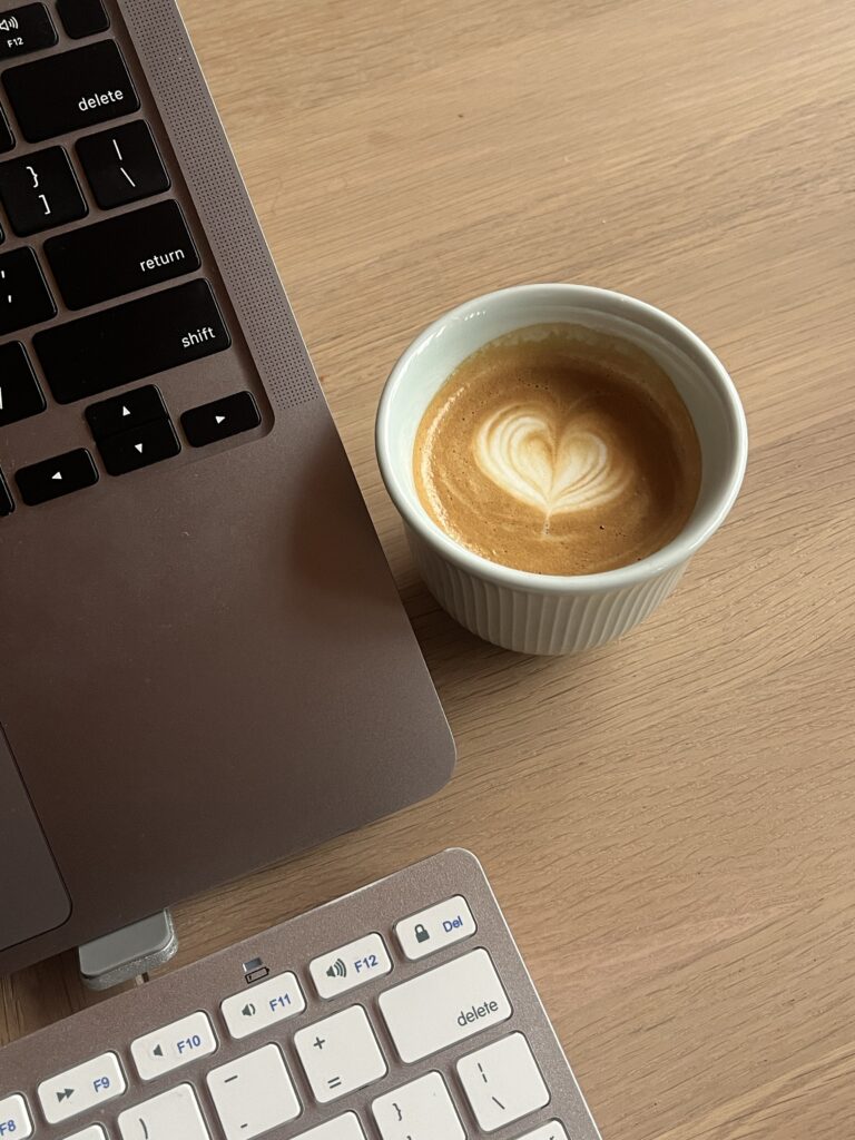 computer sitting on a desk with a coffee next to it