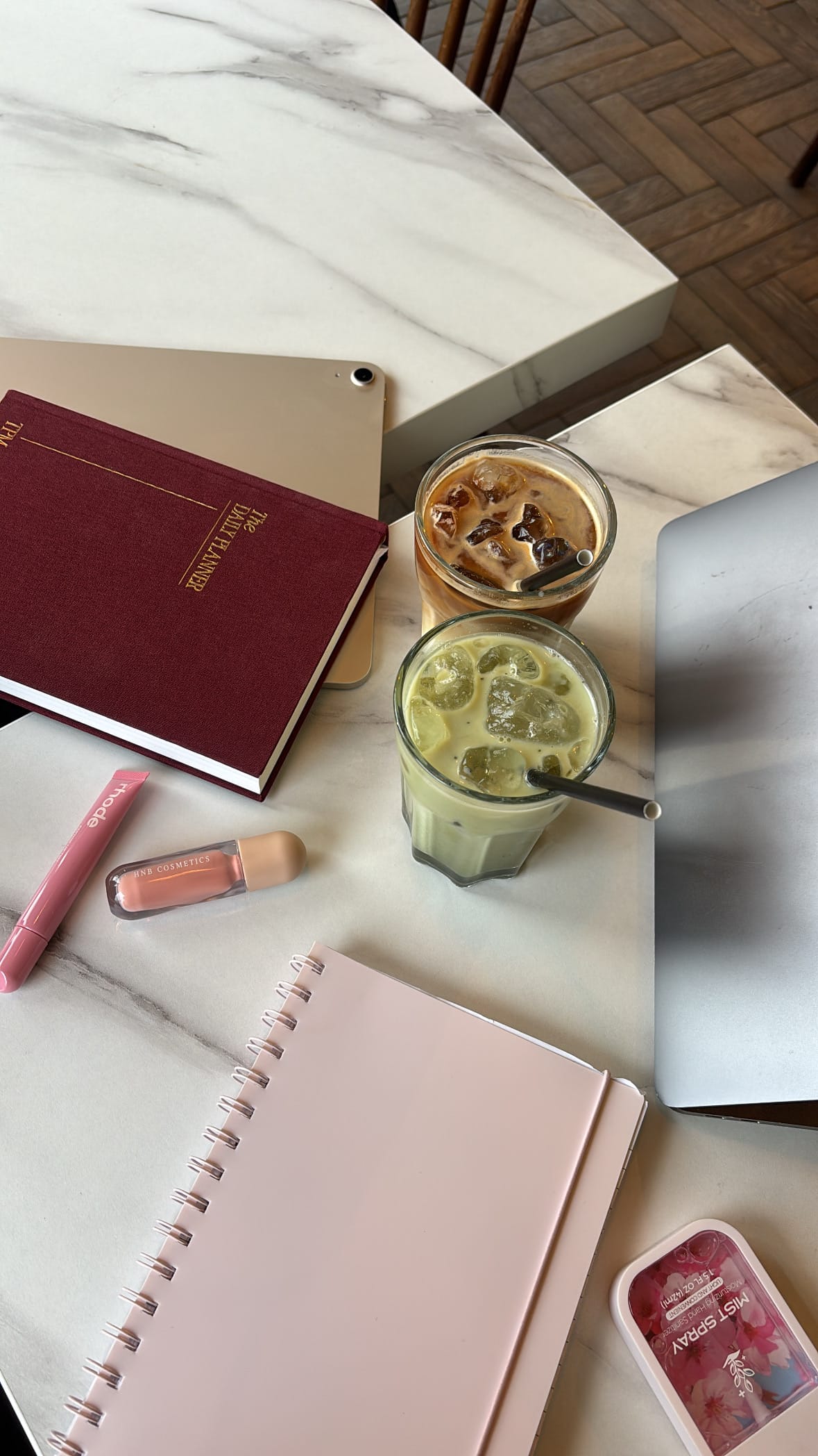 journals, pens, lip gloss, and 2 glasses of iced coffee sitting on a marble table