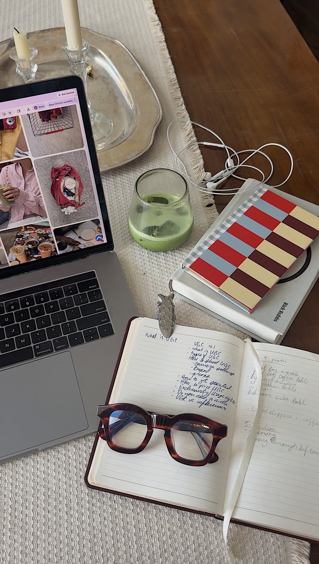 Flatlay of branding for small business workspace: laptop displaying fashion pins, green matcha glass, open planner with lists, headphones, tortoise glasses amid candles