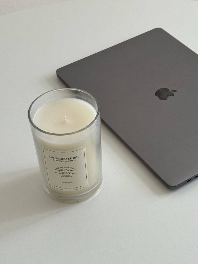 A laptop sits next to a candle on a white surface, contrasting the simplicity of a custom website design vs template