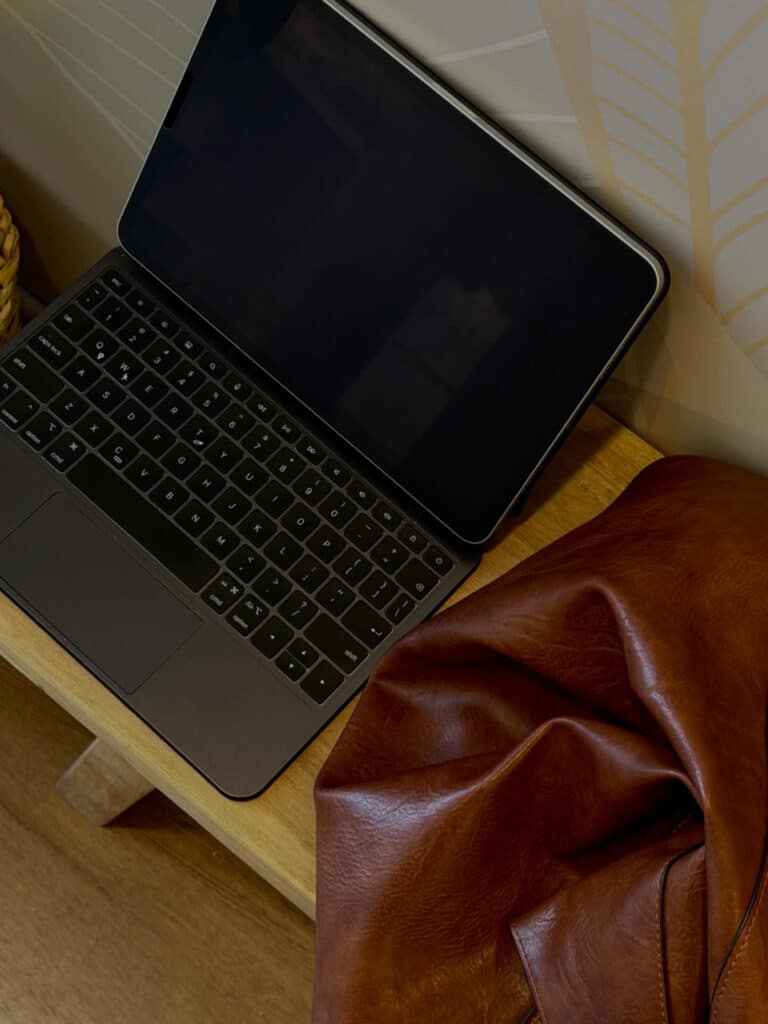 Laptop on a wooden bench near a maroon purse, a setting for reflecting on how to choose a web design company.